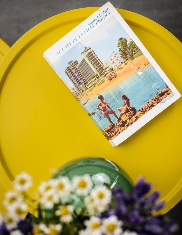 a book sitting on a yellow table with flowers at River View Boutique Apts in Ayia Napa