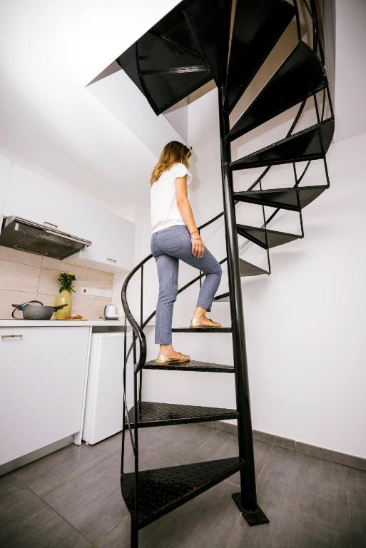 a woman standing on a spiral staircase in a kitchen at River View Boutique Apts in Ayia Napa