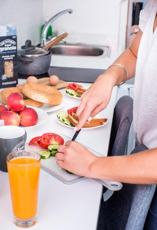 a person making a sandwich on a table with a plate of food at River View Boutique Apts in Ayia Napa