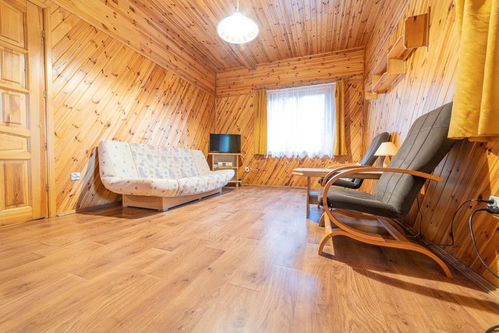 uma sala de estar com um sofá e uma mesa em Ośrodek Wrzosowa Góra - domki em Ruciane-Nida