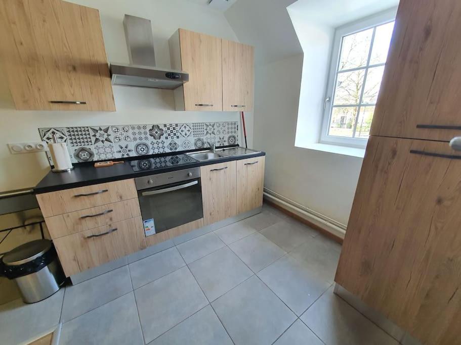 a kitchen with wooden cabinets and a stove top oven at Appartement 4 personnes proche gare et hôpital in Saint-Amand-Montrond