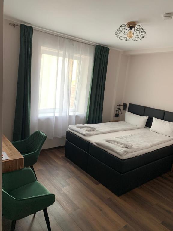 a bedroom with a large bed and a green chair at Hotel Capitol Zentrum - 24h - in Friedrichshafen