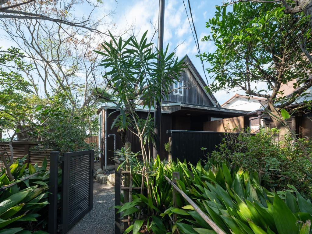 uma casa com uma cerca preta e plantas em Hayama Isshiki Beach House -葉山 一色海岸の家 - ペット可 em Hayama
