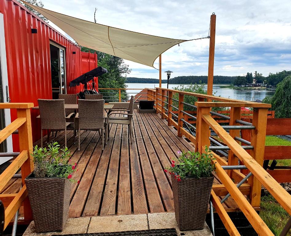 um deque de madeira com cadeiras e uma mesa com um guarda-sol em Mazury Glamping em Orzysz