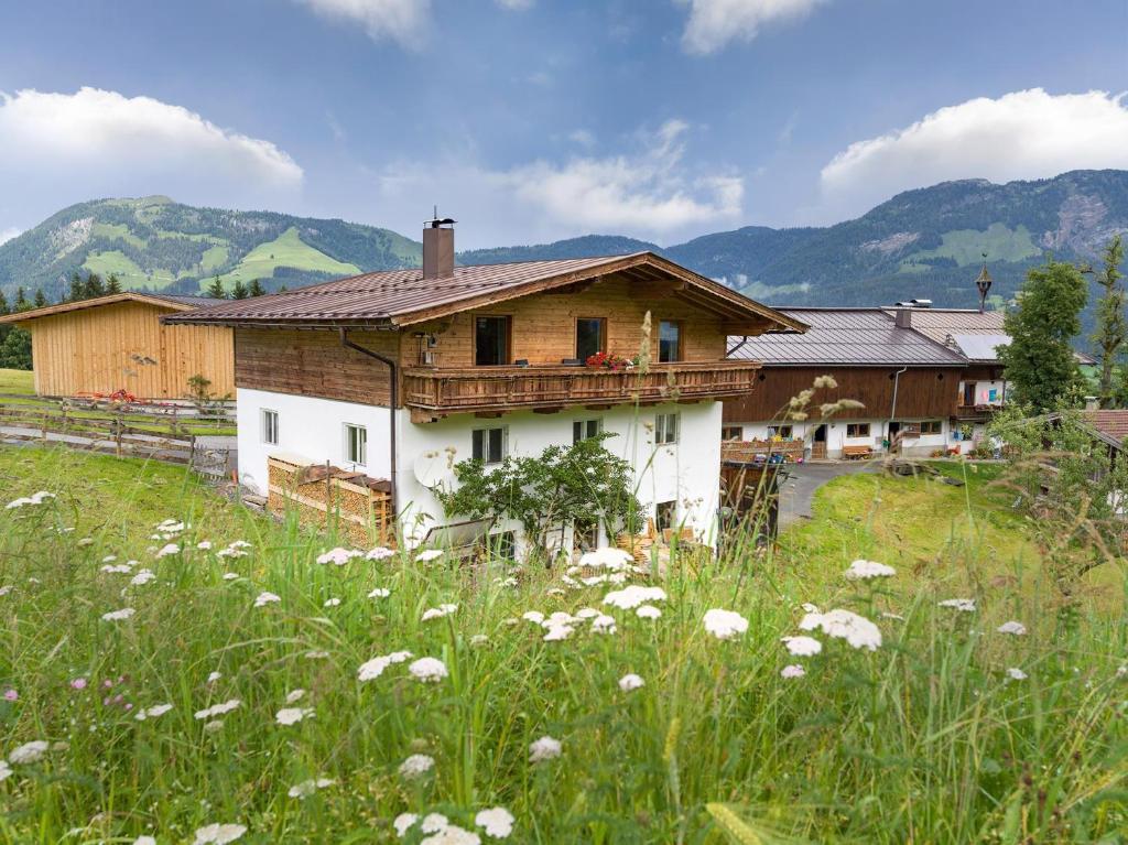 a house in a field with flowers in front of it at Wolkenmooshof in Sankt Johann in Tirol
