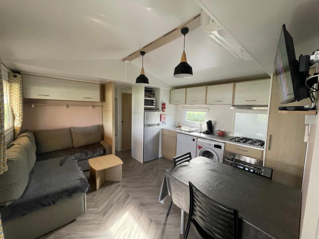 a living room and kitchen with a couch and a table at - Mobilhome Camping Les Charmettes - Fun pass non inclus - in Les Mathes