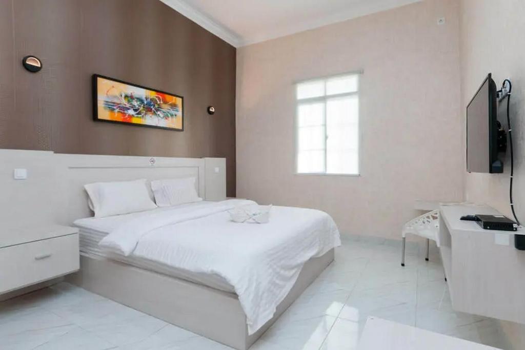 a white bedroom with a white bed and a desk at Hotel 78 Parapat Mitra RedDoorz in Parapat