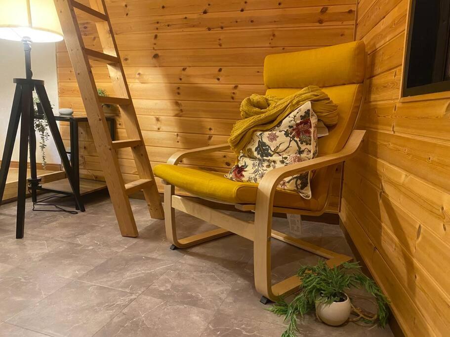 a yellow chair sitting next to a wooden wall at FTH Moon Light 3min to Sta. in Shimo-yoshida