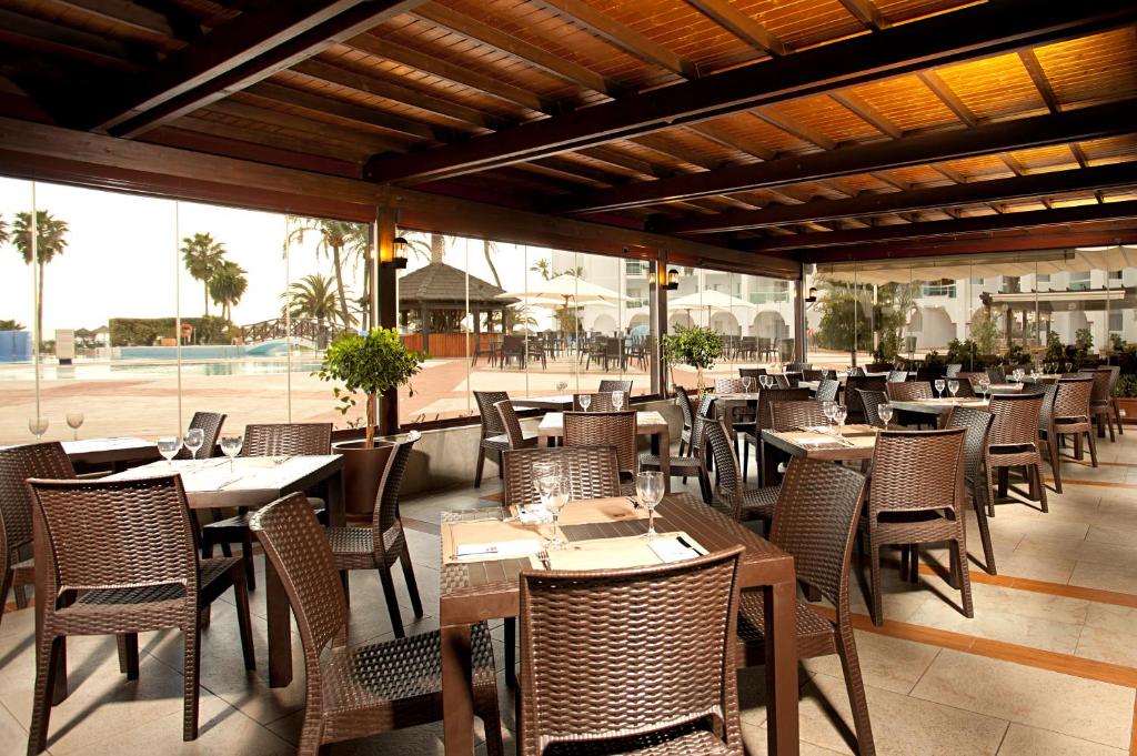a restaurant with wooden tables and chairs and a patio at Ona Marinas de Nerja Spa Resort in Nerja