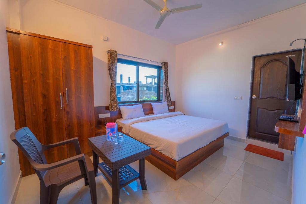 a bedroom with a bed and a table with a chair at Dhimahi Residency in Mahabaleshwar