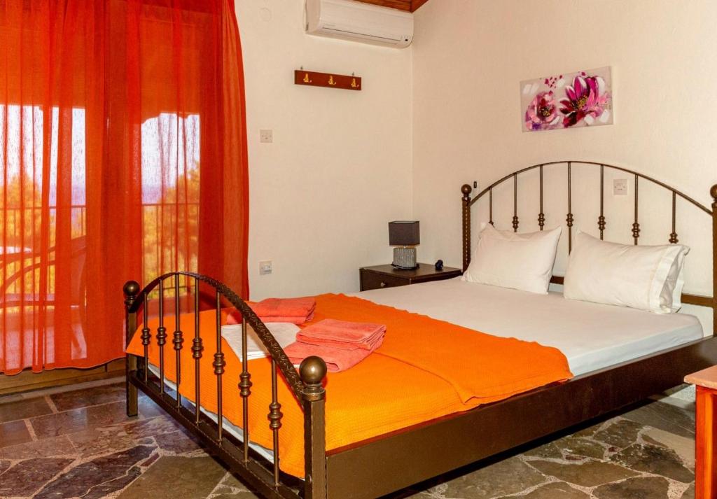 a bedroom with a bed with an orange bedspread at Pension Veria Frankfurt in Akti Salonikiou