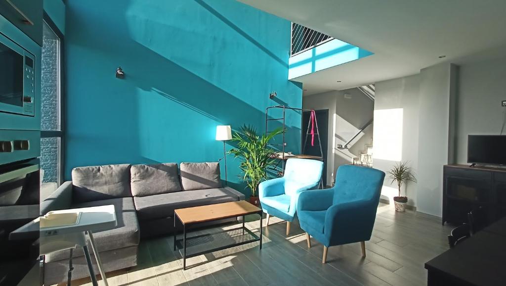 sala de estar con sofá y paredes azules en Casa Rural Pozo Cinojal, en Ahigal