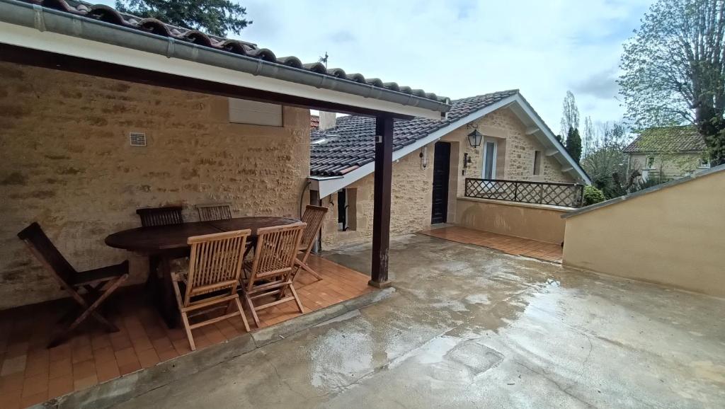 un patio al aire libre con mesa de madera y sillas en Maison T4 a 6 minutes à pieds de Sarlat en Sarlat-la-Canéda