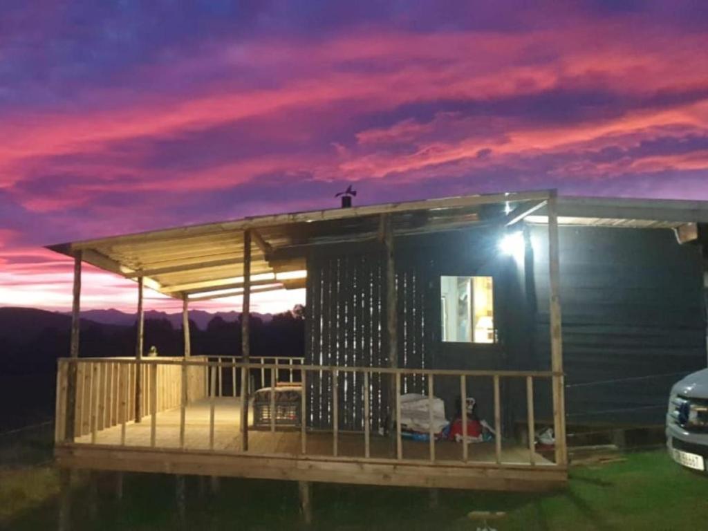 a tiny house with a deck at dusk at Tin Can Glamping Caravan in Underberg