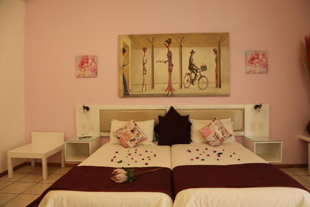 1 dormitorio con 1 cama y una pintura en la pared en Villa Ticino Guest House en Sabie