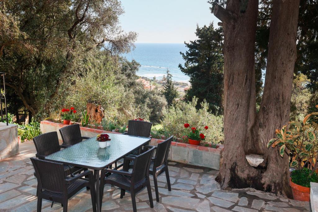una mesa y sillas en un patio con vistas al océano en Amaryllis Seaview House by GuestCorfu, en Corfú