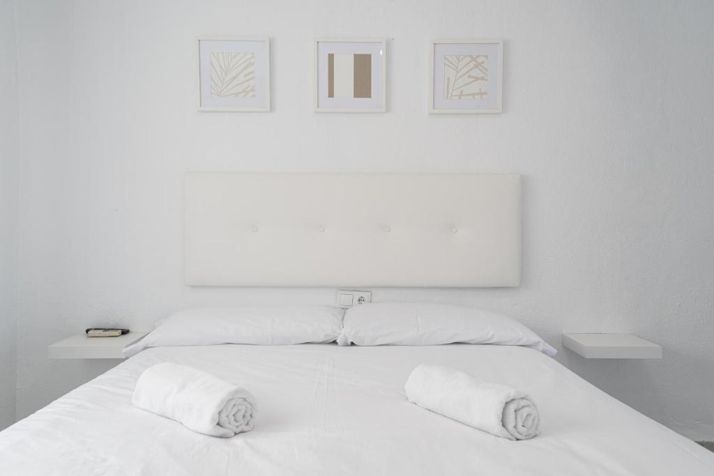 1 dormitorio blanco con 1 cama blanca y 2 almohadas en Hostal Alicia, en Marbella