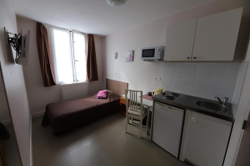 um pequeno quarto com uma cama e uma cozinha em Hôtel du Roussillon em Paris