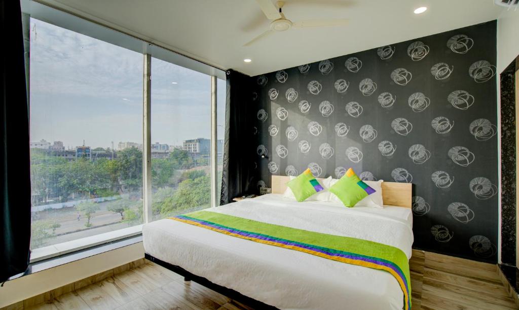 a bedroom with a large bed and a large window at Treebo Trend Grand Lotus in Surat