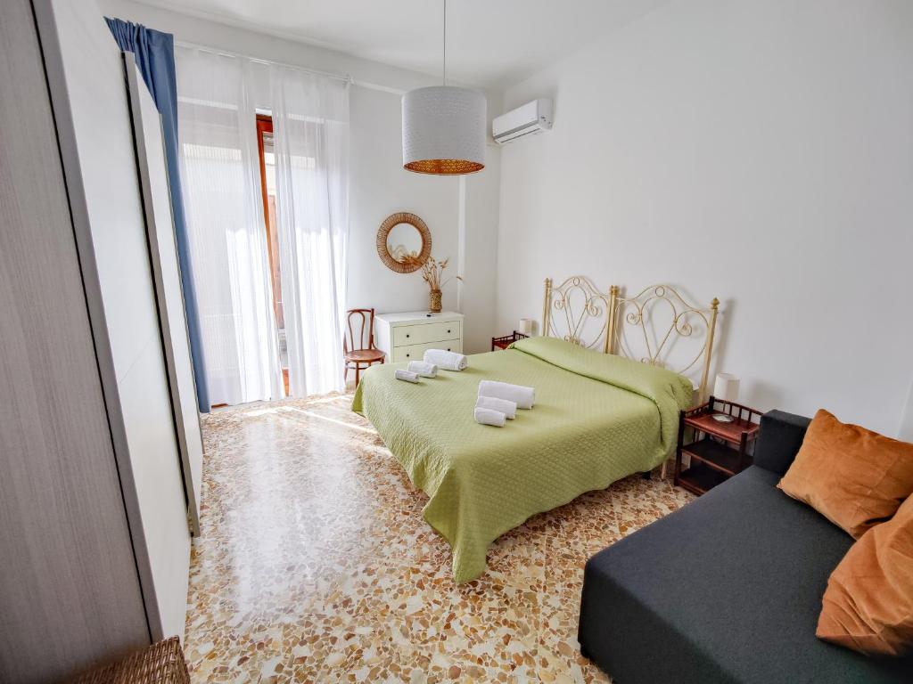 a bedroom with a green bed and a couch at Fermata Cappuccini in Acireale