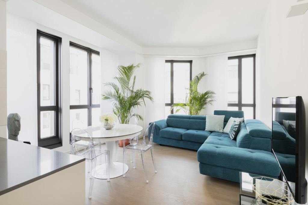 uma sala de estar com um sofá azul e uma mesa em Easylife - Lussuosa dimora con rooftop vista Duomo em Milão
