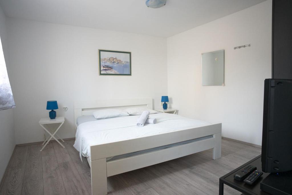 ein weißes Schlafzimmer mit einem Bett und einem Fernseher in der Unterkunft Apartment Fly in Split