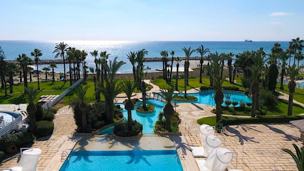 an aerial view of a resort with a pool and the ocean at Sandy Beach Hotel & Spa - ex Sentido in Larnaca