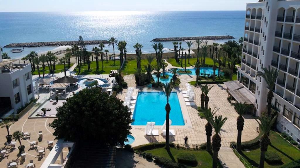 an aerial view of a resort with a pool and the ocean at Sandy Beach Hotel & Spa - ex Sentido in Larnaca