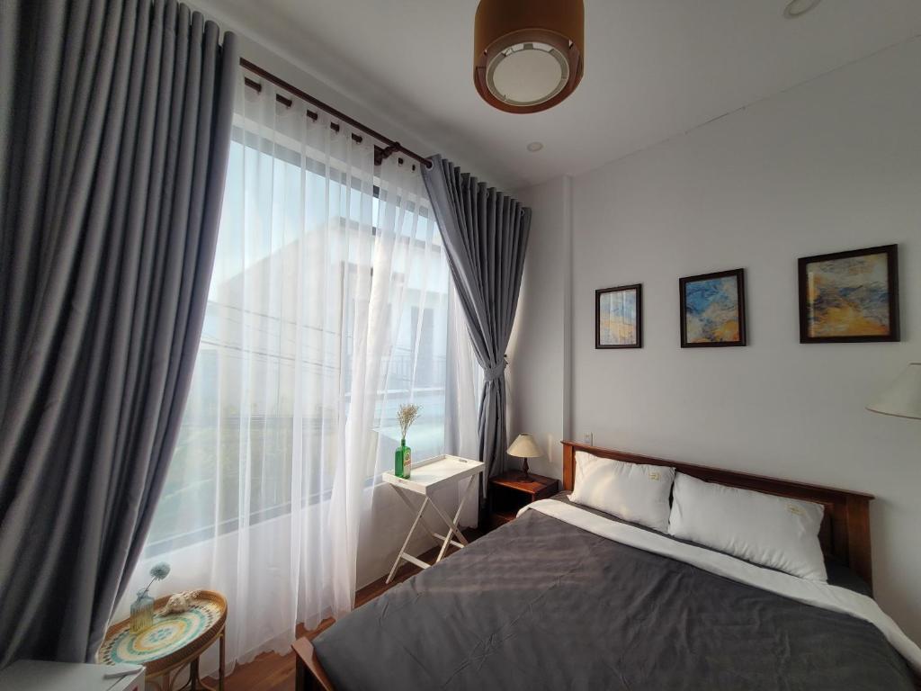 a bedroom with a bed and a large window at MIHA Villa & Stay in Cái Răng