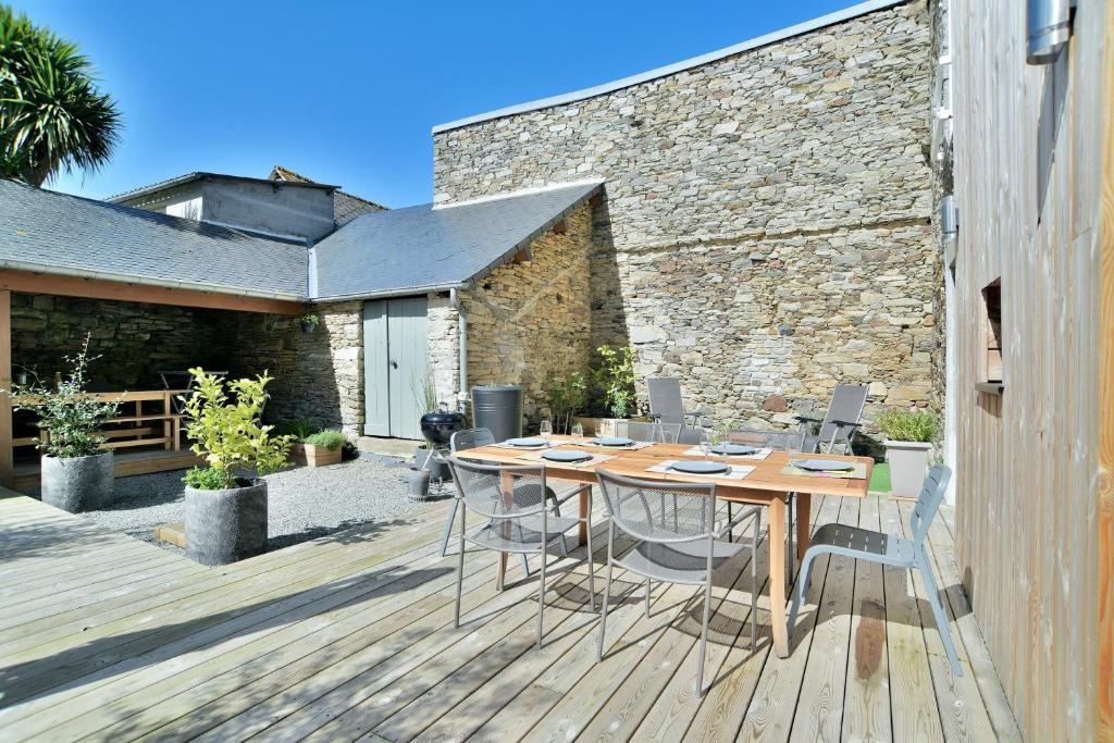 a patio with a wooden table and chairs on a deck at Ty Karet - Maison pour 6 proche plage in Saint-Cast-le-Guildo