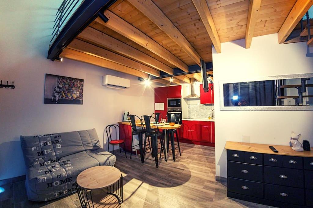 ein Wohnzimmer und eine Küche mit einem Sofa und einem Tisch in der Unterkunft Le clos de Tanvol 2 -parking gratuit- climatisation-terrasse in Viriat
