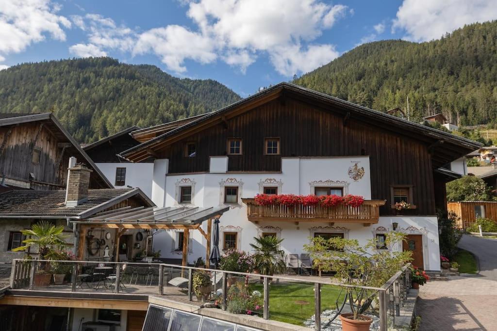 ein Haus in den Bergen mit roten Blumen auf dem Balkon in der Unterkunft Gidnhof in Trins