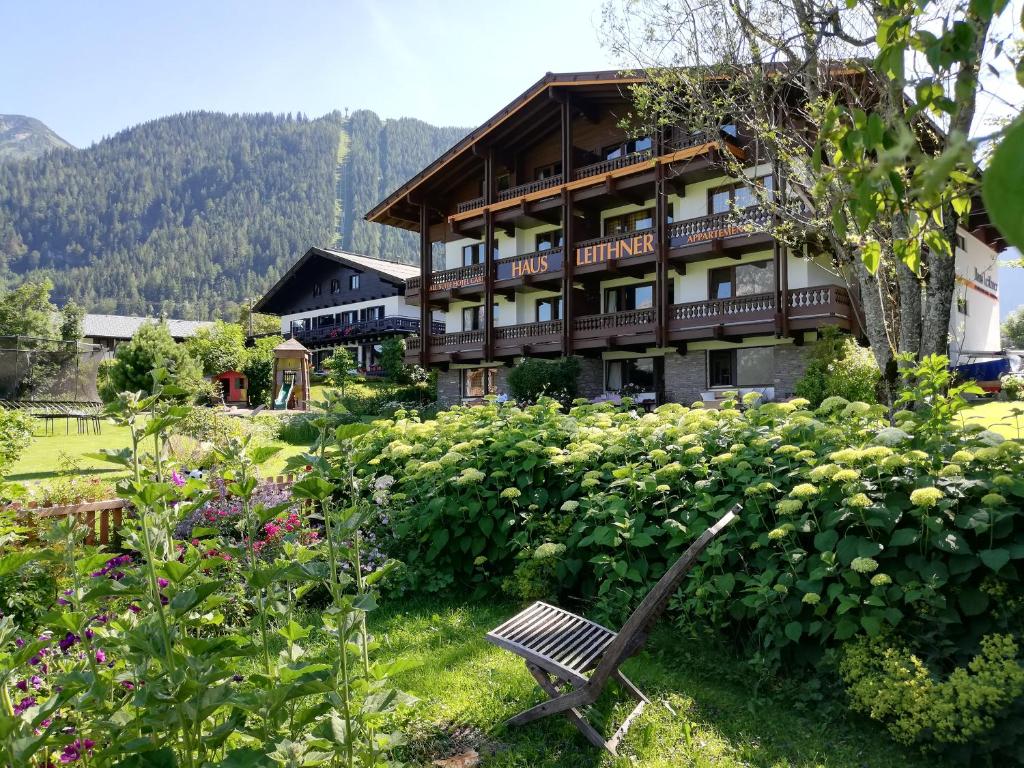 un banc dans un jardin en face d'un bâtiment dans l'établissement All Suite Hotel Garni Leithner, à Pertisau