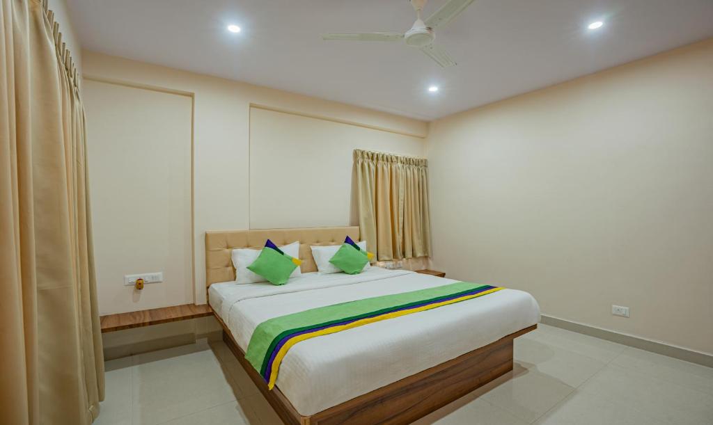 a bedroom with a large bed with green pillows at Treebo Trend Globel Stay - Uttarahalli in Bangalore