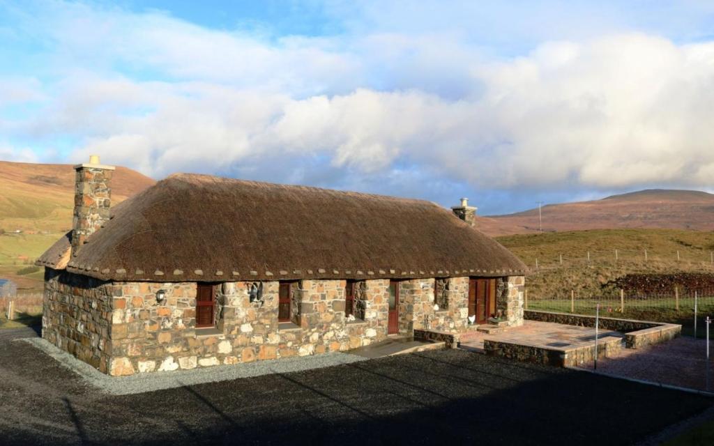 an old stone building with a thatch roof at Fairy Glen Cottage in Uig