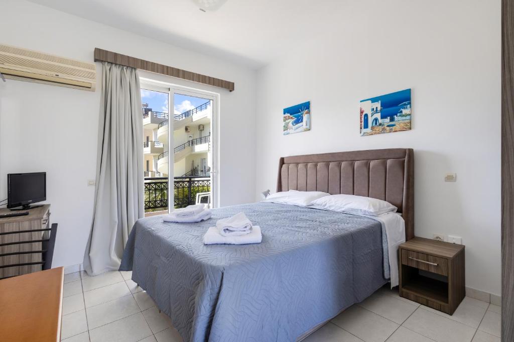 a bedroom with a bed and a large window at Johnhara Studios & Apartments in Ialysos