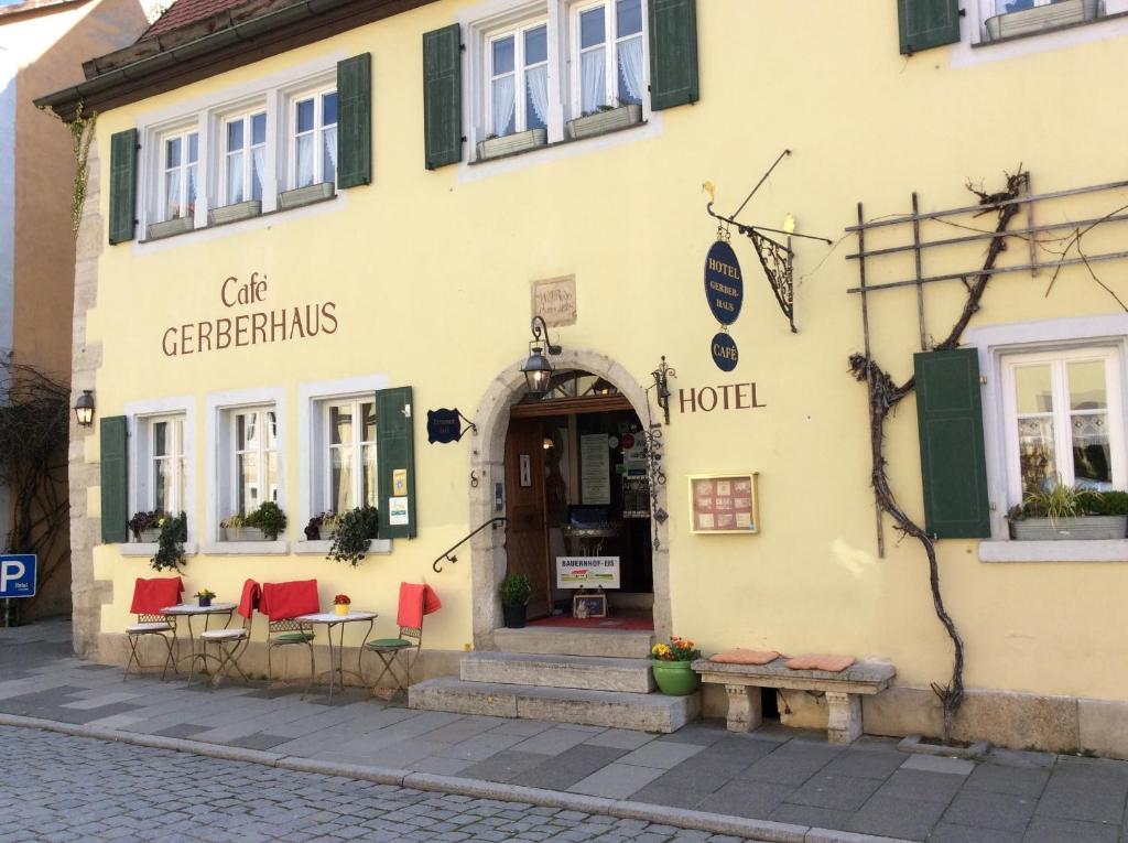 ein gelbes Gebäude mit Tischen und Stühlen davor in der Unterkunft Hotel Gerberhaus in Rothenburg ob der Tauber