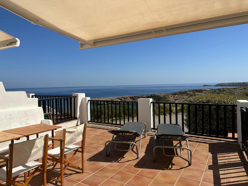 eine Terrasse mit einem Tisch, Stühlen und Meerblick in der Unterkunft ALDEAMAR F1 by SOM Menorca in Son Parc