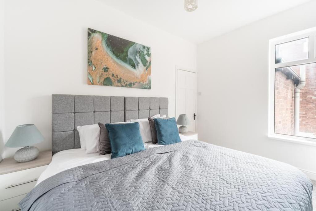 biała sypialnia z dużym łóżkiem z niebieskimi poduszkami w obiekcie Cosy home near Port of Hull w mieście Hull