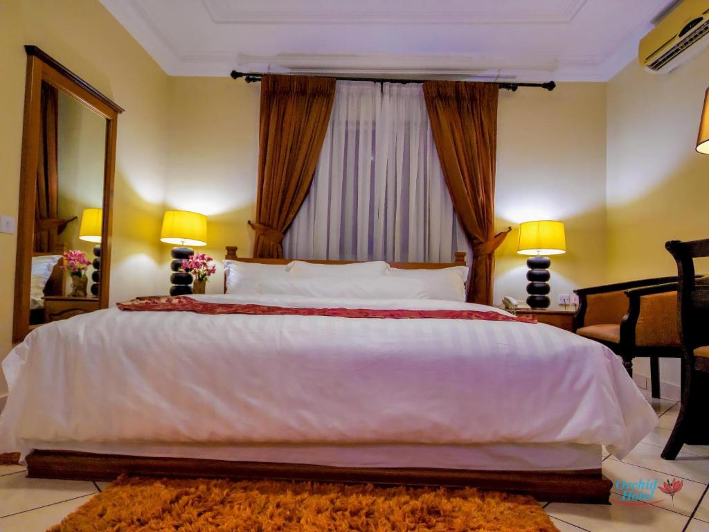 a bedroom with a large white bed with a large window at Orchid Hotel in Accra