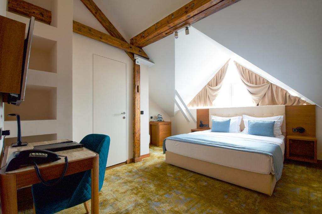 a bedroom with a bed and a desk and a window at Hotel City Savoy in Belgrade