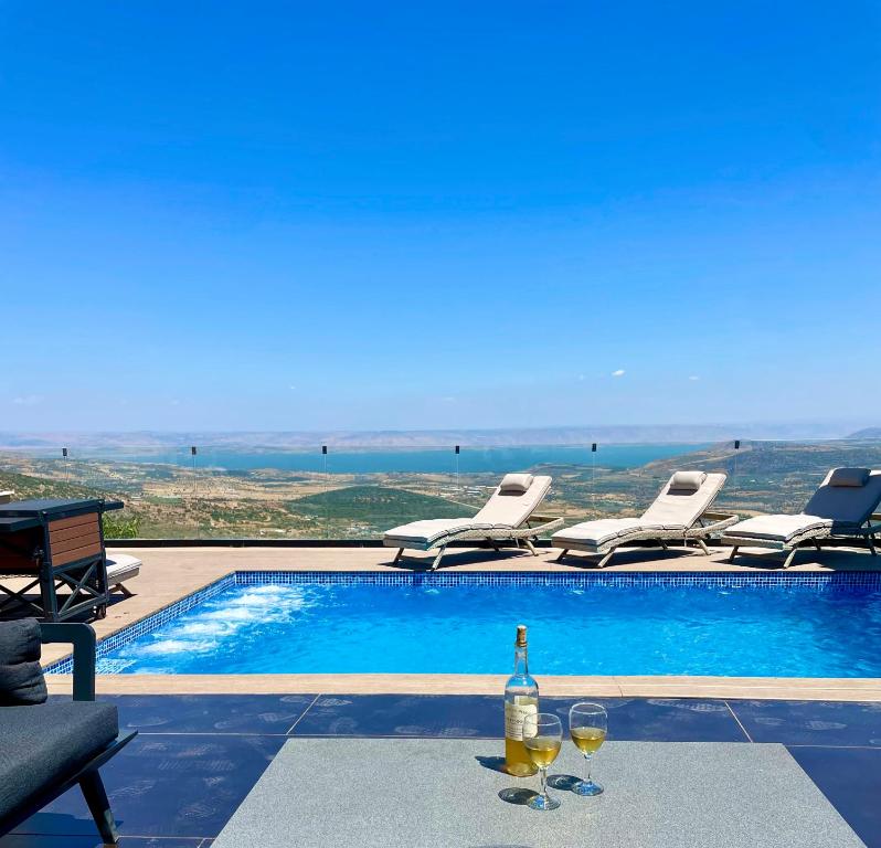 una botella de vino sentada en una mesa junto a la piscina en Galilee Hills - Resort & Suites, en Maghār