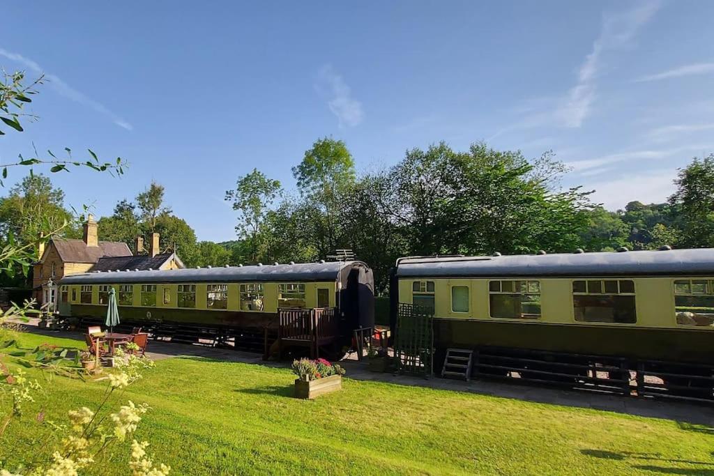 twee groene treinwagons geparkeerd in een tuin bij Carriage 2 - Coalport Station Holidays in Telford