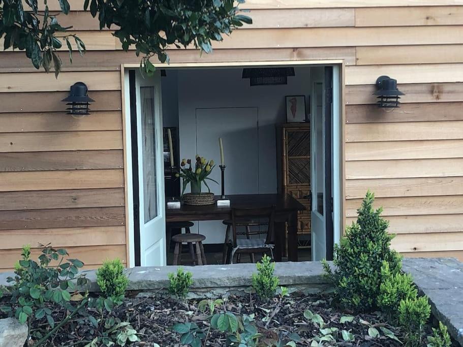 a sliding glass door of a house with a table at Stylish Cottage in the Pewsey Vale in Marlborough