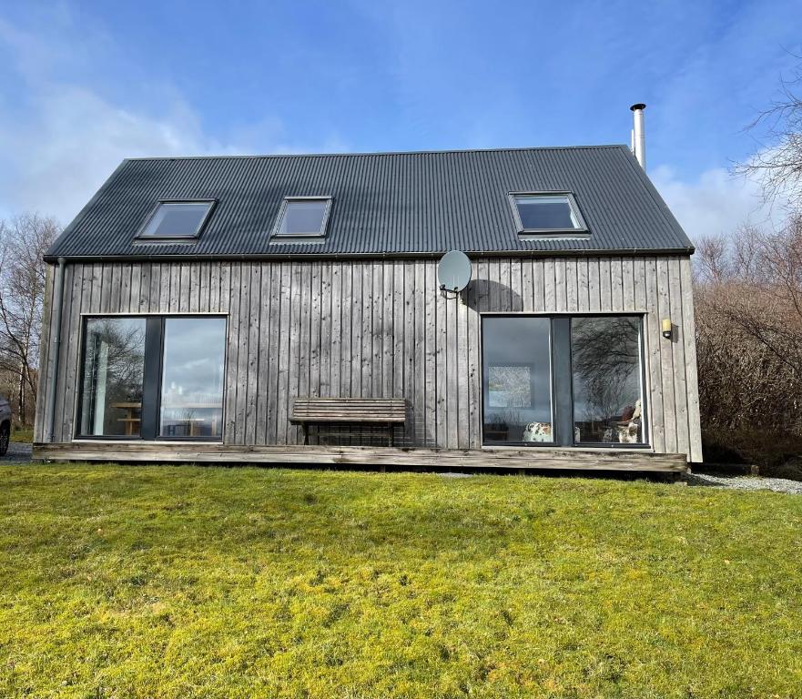 a house with a bench in the front of it at Skeabost Wood Cottage in Skeabost