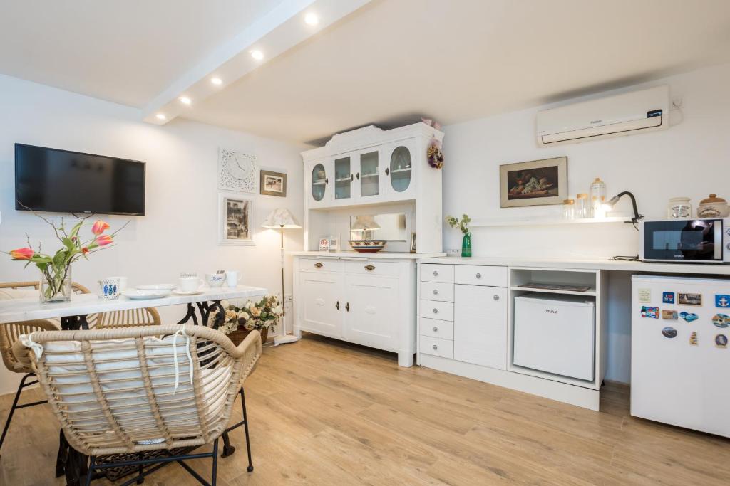 una cucina con armadi bianchi, tavolo e sedie di Charming Studio apartment at House Rustica with terrace and nearby parking a Punat
