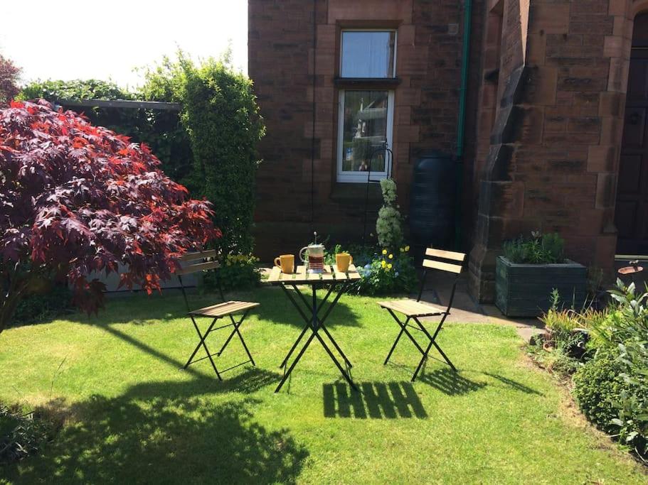 a garden with a table and two chairs in the grass at Beautiful Apartment in Character Former Rectory in Penrith