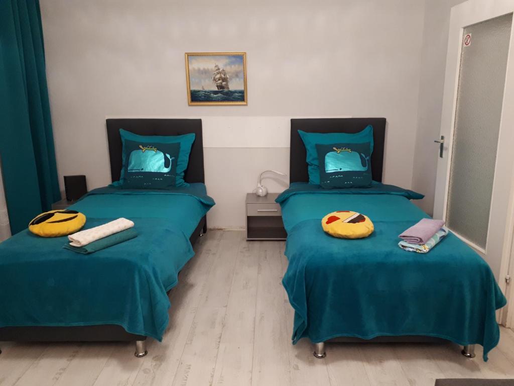 2 camas en una habitación con sábanas verdes y almohadas amarillas en Comfort, en Hannover