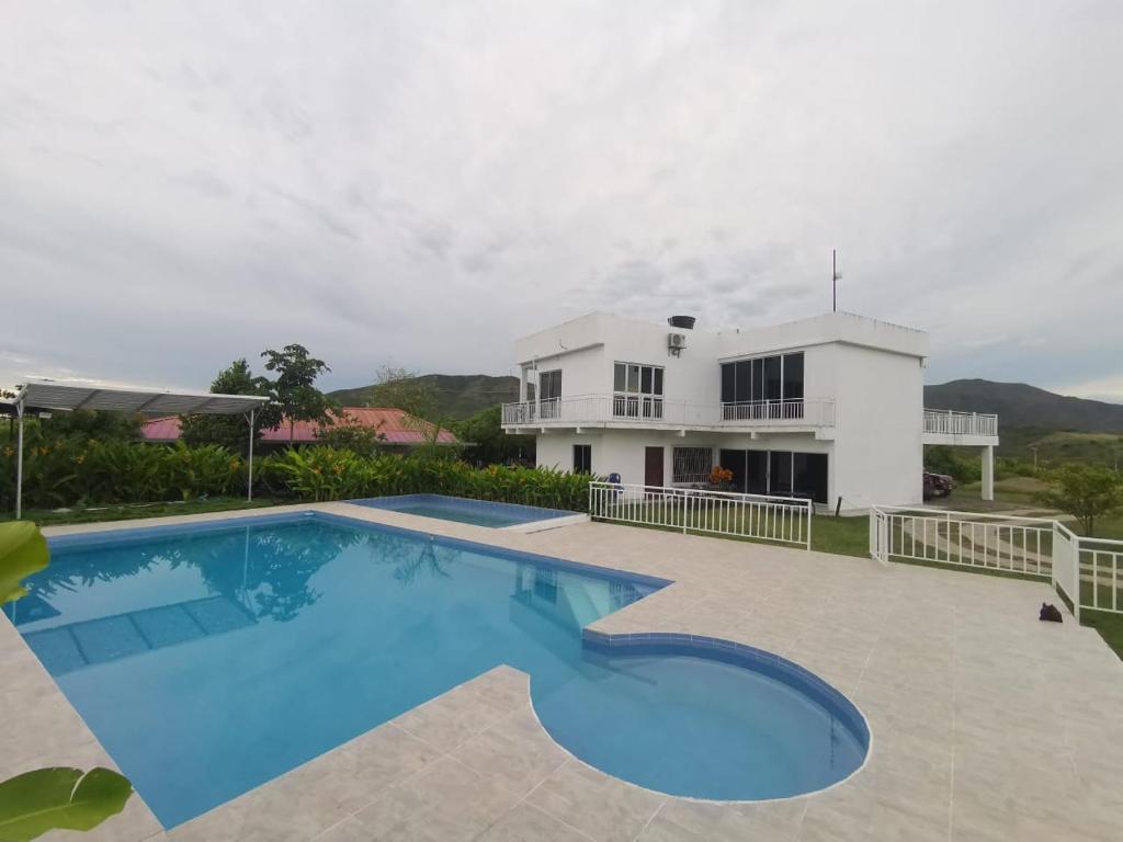 a villa with a swimming pool in front of a house at QUINTA RANCHO SANTIAGO CAMPESTRE capacidad 50 huéspedes in Yaguará