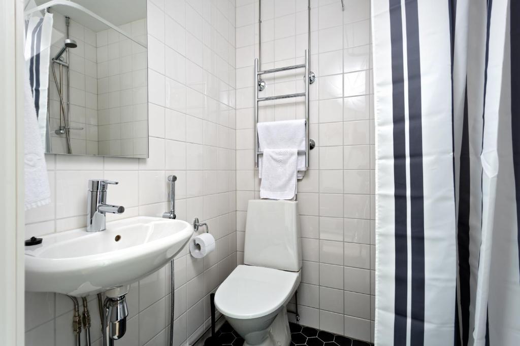 a white bathroom with a toilet and a sink at Forenom Serviced Apartments Helsinki Kruununhaka in Helsinki